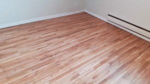 Plancher restauré après travaux de réparation et vernissage professionnel à Montréal.