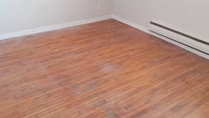 Plancher de bois franc endommagé avant travaux de restauration à Montréal.